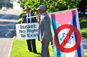 Henry Herskovitz, founder of an anti-Israel protest group in Ann Arbor, and Donald Abdul Roberts, holding an anti-Israel flag, kick off another day of protesting outside the Beth Israel Congregation on Washtenaw Avenue on a Saturday morning in August 2013.Ryan Stanton | The Ann Arbor News