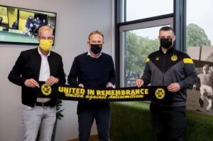 Borussia Dortmund managing director Carsten Cramer, CEO Hans-Joachim Watzke, and head of corporater responsibility Daniel Lörcher (from left to right) with a scarf promoting the team's anti-Semitism education efforts. Alexandre Simoes / Borussia Dortmund